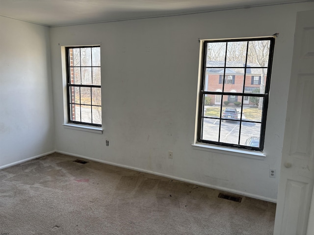 spare room featuring carpet, visible vents, and baseboards