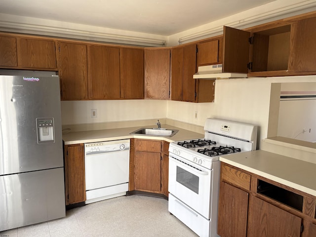 kitchen with brown cabinets, under cabinet range hood, a sink, white appliances, and light countertops