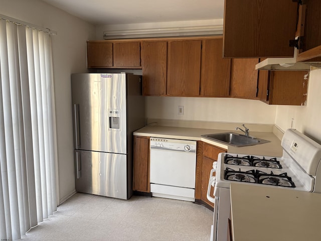 kitchen featuring white appliances, light floors, a sink, light countertops, and brown cabinets