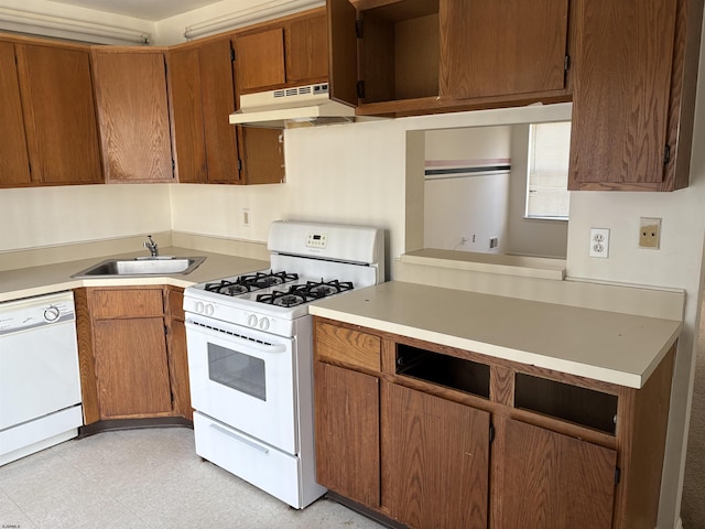 kitchen with under cabinet range hood, a sink, white appliances, light countertops, and light floors