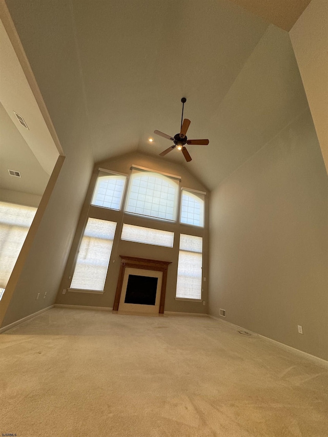 unfurnished living room with visible vents, ceiling fan, light carpet, a fireplace, and high vaulted ceiling