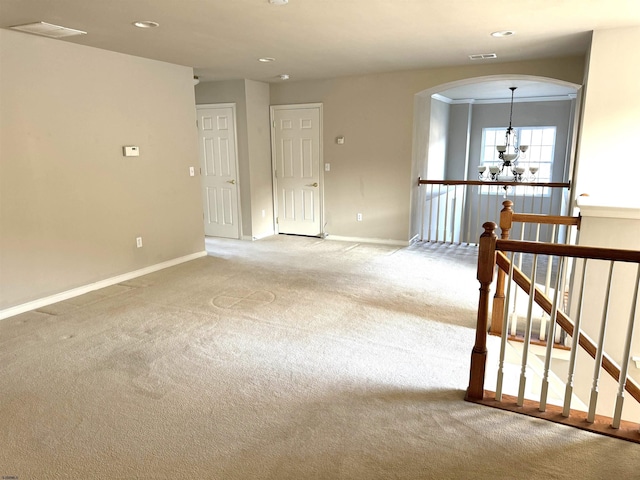 unfurnished room featuring visible vents, baseboards, light carpet, arched walkways, and a notable chandelier