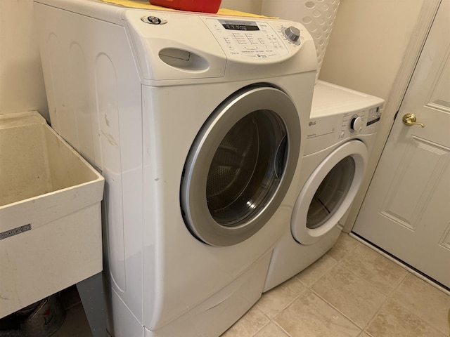 laundry room with light tile patterned flooring, laundry area, washing machine and dryer, and a sink