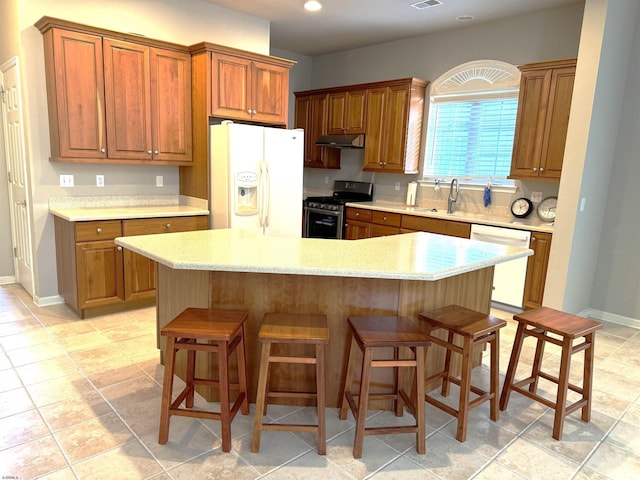 kitchen with a sink, white appliances, a breakfast bar, and light countertops