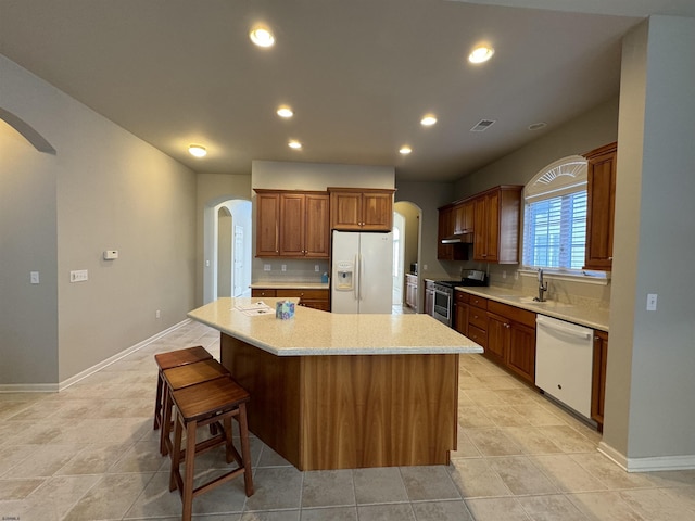 kitchen featuring white appliances, recessed lighting, arched walkways, and a center island