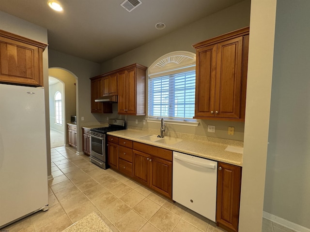 kitchen with white appliances, visible vents, arched walkways, a sink, and light countertops