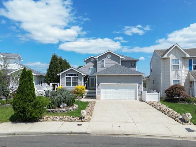 traditional home with concrete driveway, fence, a garage, and roof with shingles