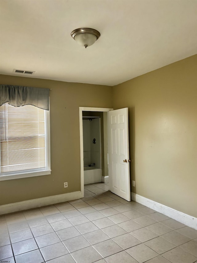 empty room featuring light tile patterned floors, visible vents, and baseboards