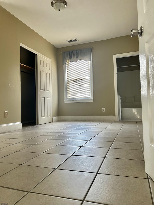 unfurnished bedroom featuring visible vents, baseboards, a closet, and light tile patterned flooring