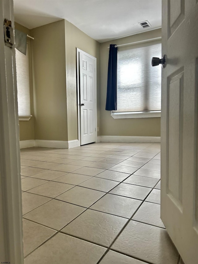 spare room featuring light tile patterned floors, visible vents, and baseboards