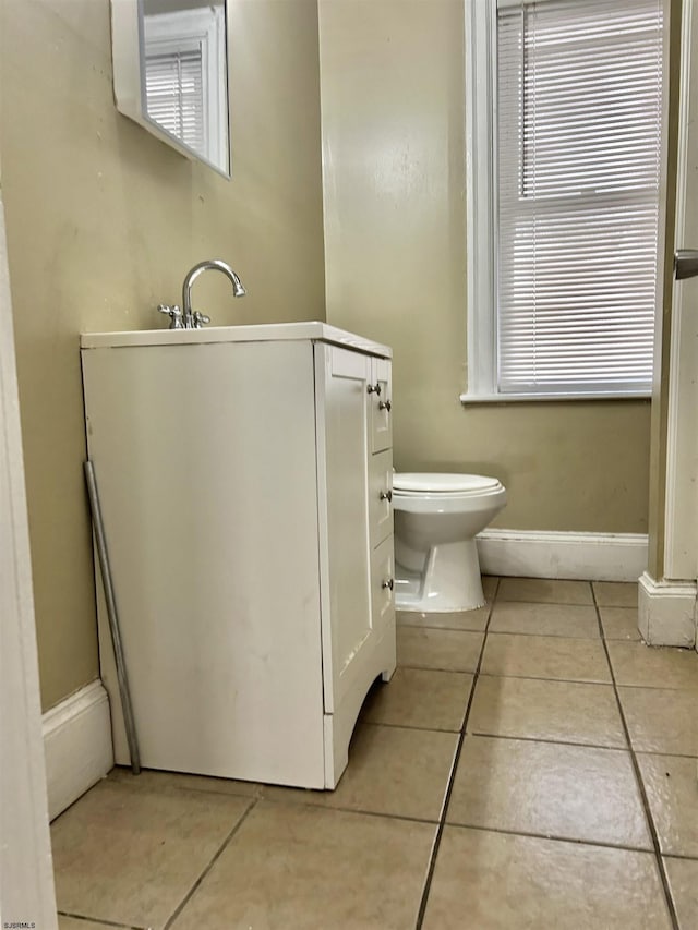 bathroom with tile patterned floors, plenty of natural light, toilet, and baseboards