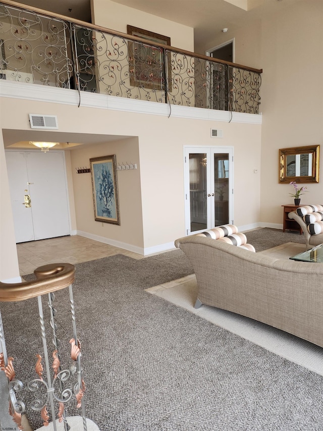 carpeted living room with french doors, visible vents, a towering ceiling, and baseboards