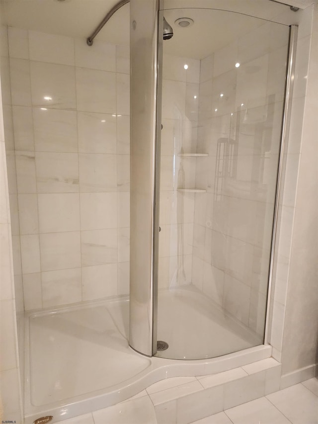 bathroom with a shower stall and tile patterned flooring