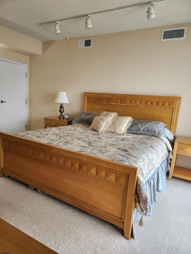 carpeted bedroom featuring a ceiling fan, visible vents, and a textured ceiling