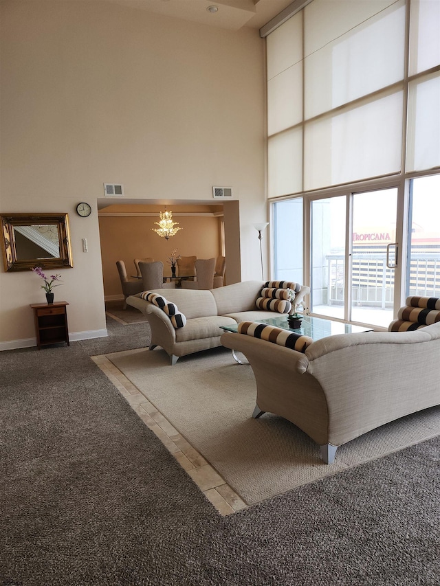 living room featuring a high ceiling, carpet, visible vents, and a chandelier