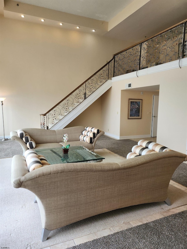 living area featuring recessed lighting, baseboards, light colored carpet, and a towering ceiling