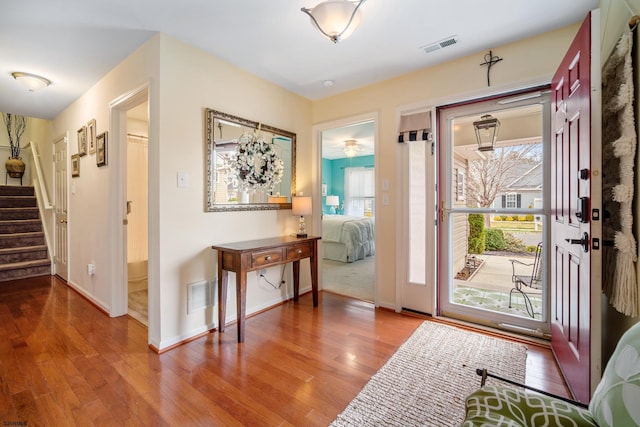 entrance foyer with stairway, visible vents, and wood finished floors