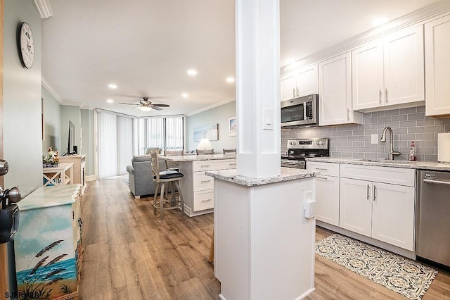 kitchen featuring a center island, stainless steel appliances, crown molding, and a sink