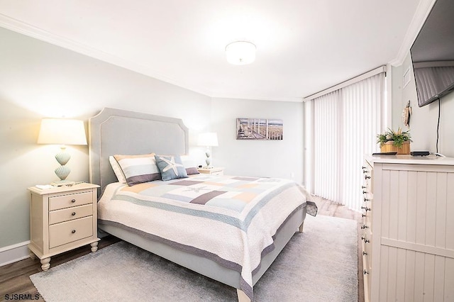 bedroom with ornamental molding, baseboards, and wood finished floors