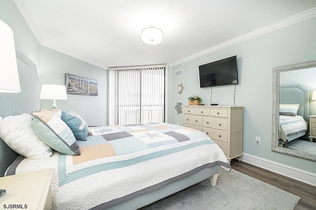 bedroom with baseboards, wood finished floors, visible vents, and ornamental molding