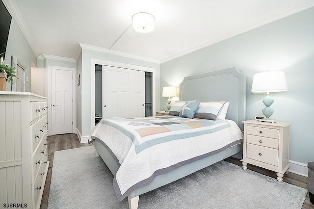 bedroom with a closet, baseboards, wood finished floors, and ornamental molding