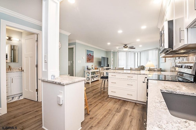 kitchen with a kitchen bar, crown molding, white cabinetry, and ornate columns