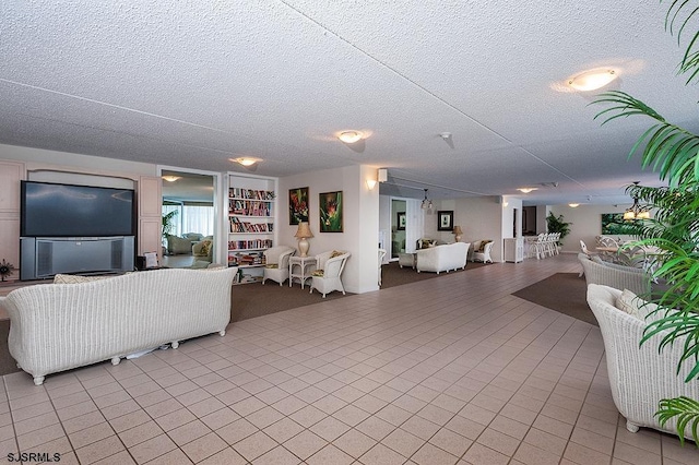 living room featuring light tile patterned flooring, built in shelves, and a textured ceiling