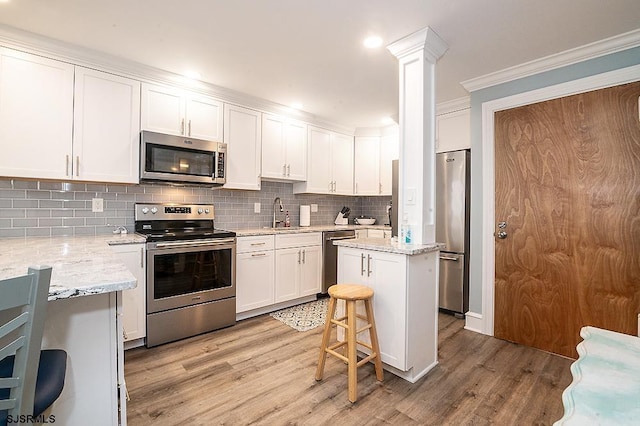 kitchen with light wood-style floors, tasteful backsplash, appliances with stainless steel finishes, and crown molding