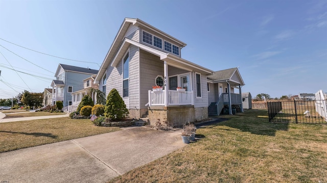 view of front facade with covered porch, a front yard, and fence