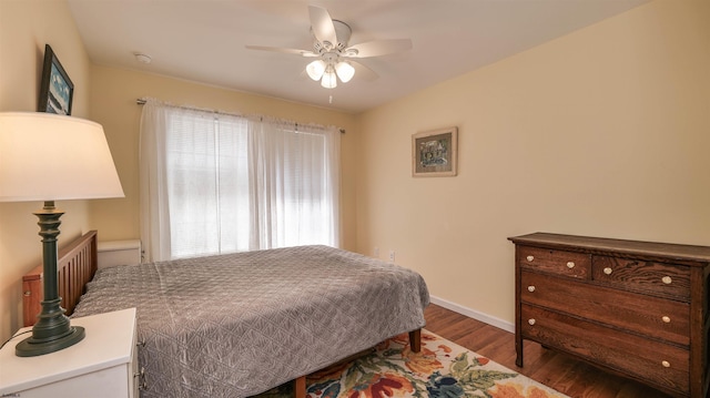 bedroom featuring multiple windows, wood finished floors, baseboards, and ceiling fan