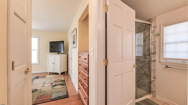 full bath featuring baseboards, vanity, wood finished floors, and a shower stall