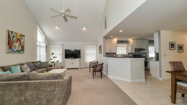 living area with light tile patterned floors, baseboards, high vaulted ceiling, and a ceiling fan