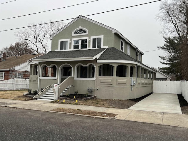 view of front of property with a shingled roof, fence, covered porch, and stucco siding