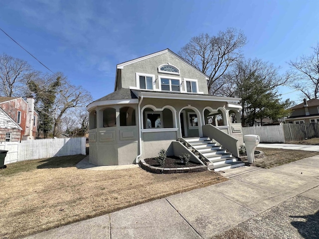 view of front of home with stucco siding, a porch, and fence