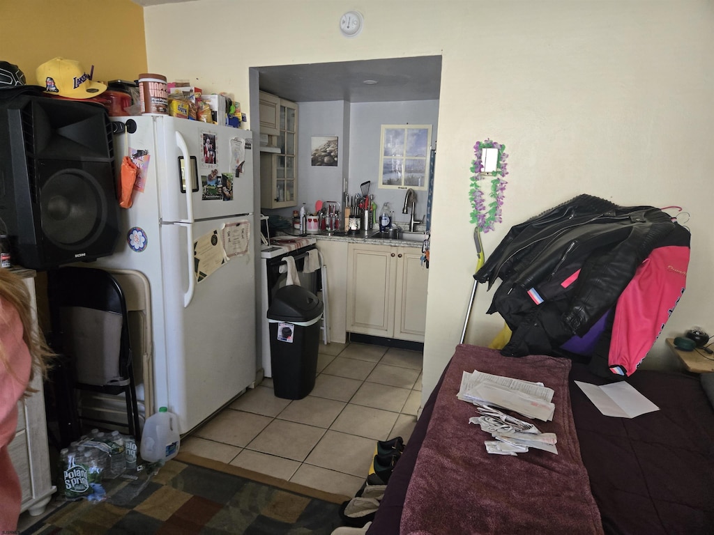 kitchen featuring light countertops, light tile patterned floors, freestanding refrigerator, and a sink