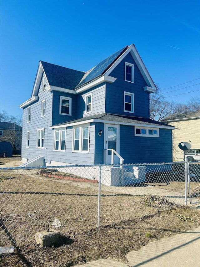 view of front facade featuring a fenced front yard and roof mounted solar panels