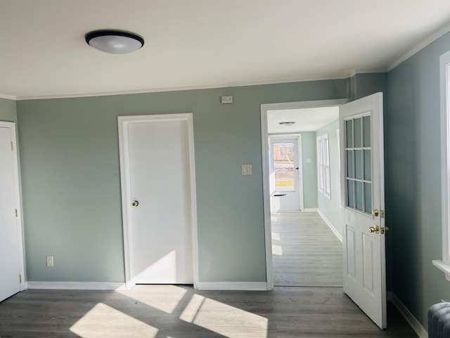 interior space with baseboards, wood finished floors, radiator heating unit, and ornamental molding