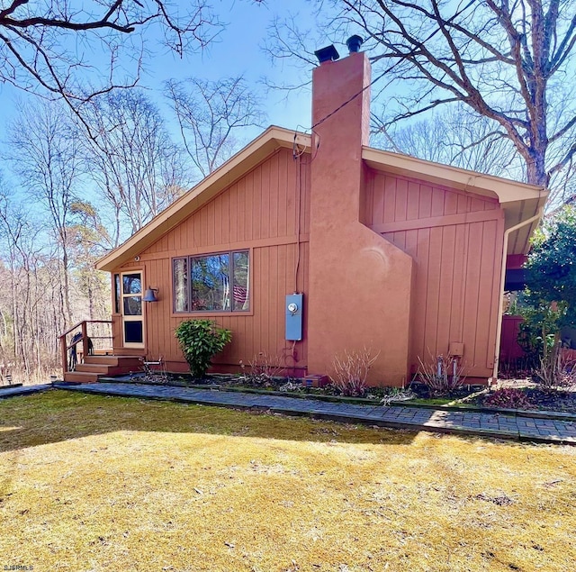 view of side of property featuring a lawn and a chimney