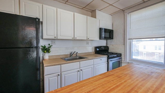 kitchen with black appliances, a sink, white cabinetry, decorative backsplash, and a paneled ceiling