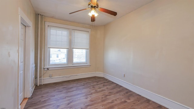 empty room featuring wood finished floors, baseboards, and ceiling fan