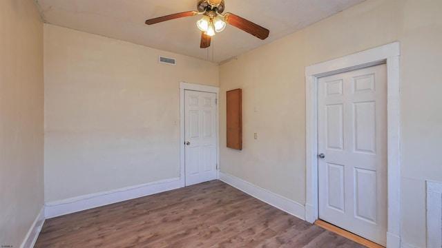 spare room featuring visible vents, wood finished floors, baseboards, and ceiling fan