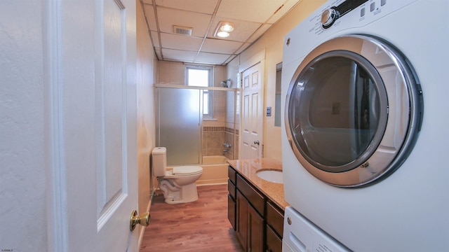 bathroom with vanity, wood finished floors, visible vents, stacked washer / dryer, and toilet