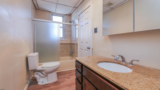 full bath featuring visible vents, toilet, wood finished floors, enclosed tub / shower combo, and vanity