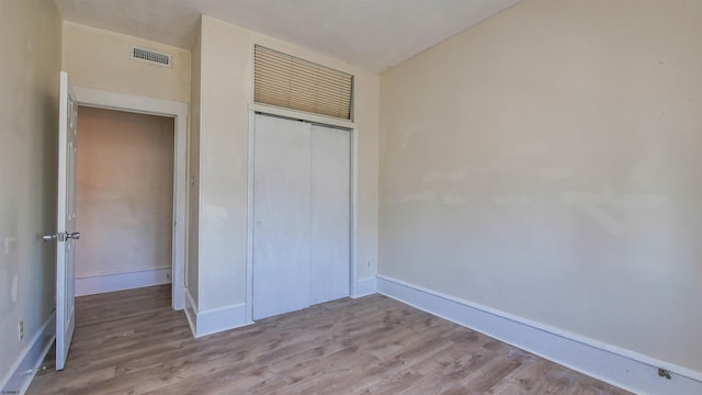 unfurnished bedroom with visible vents, baseboards, a closet, and wood finished floors