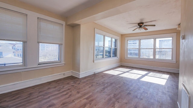 spare room featuring visible vents, baseboards, wood finished floors, and a ceiling fan