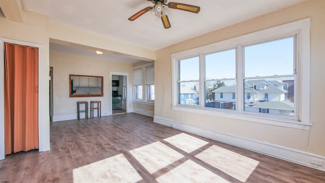 unfurnished living room featuring a ceiling fan, wood finished floors, and baseboards