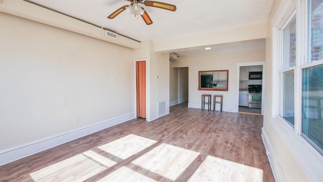 unfurnished living room featuring ceiling fan, light wood-style floors, visible vents, and baseboards