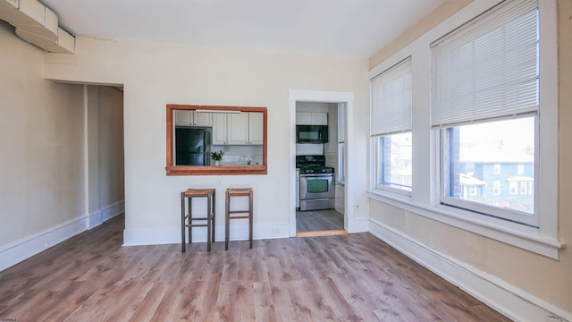 kitchen with black appliances, baseboards, and wood finished floors