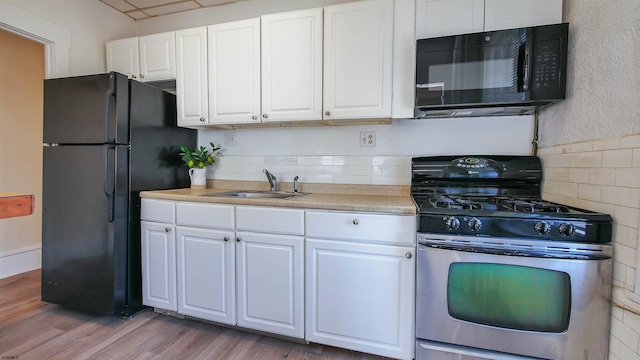 kitchen featuring wood finished floors, white cabinets, black appliances, and a sink