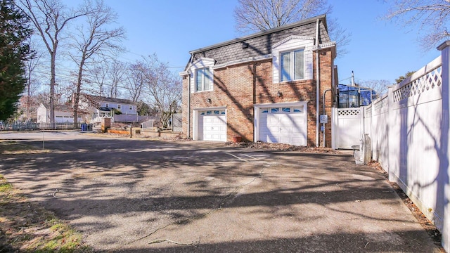 102 Morris Ave, Linwood, NJ 08221 - view of side of property featuring fence, mansard roof, a garage, aphalt driveway, and brick siding